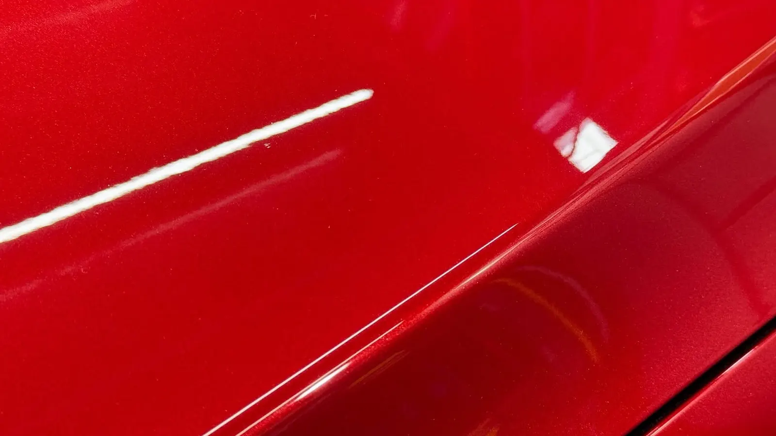 Capot rojo pulido con el reflejo limpio de un tubo de luz